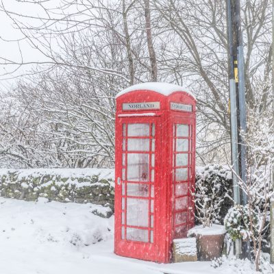 A traditional red British telephone box in the snow in winter